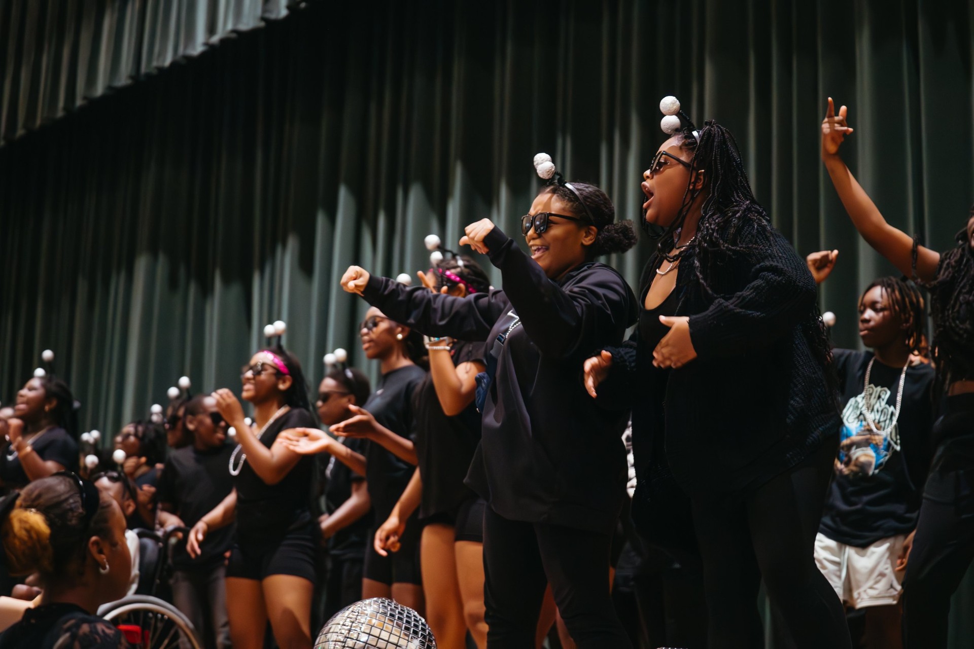 Students performing on stage in matching black outfits